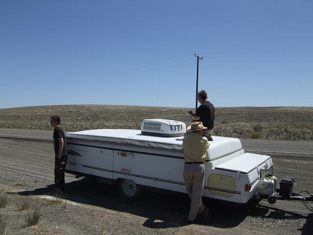 Curtis is repairing the tear in the AC cover. Anthony and Jeff are supervising.