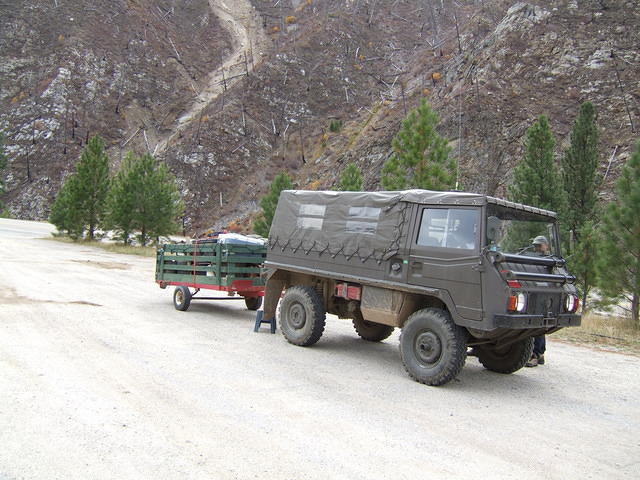 The trailer does not seem as full. The damage from a forest fire can be seen in the background.